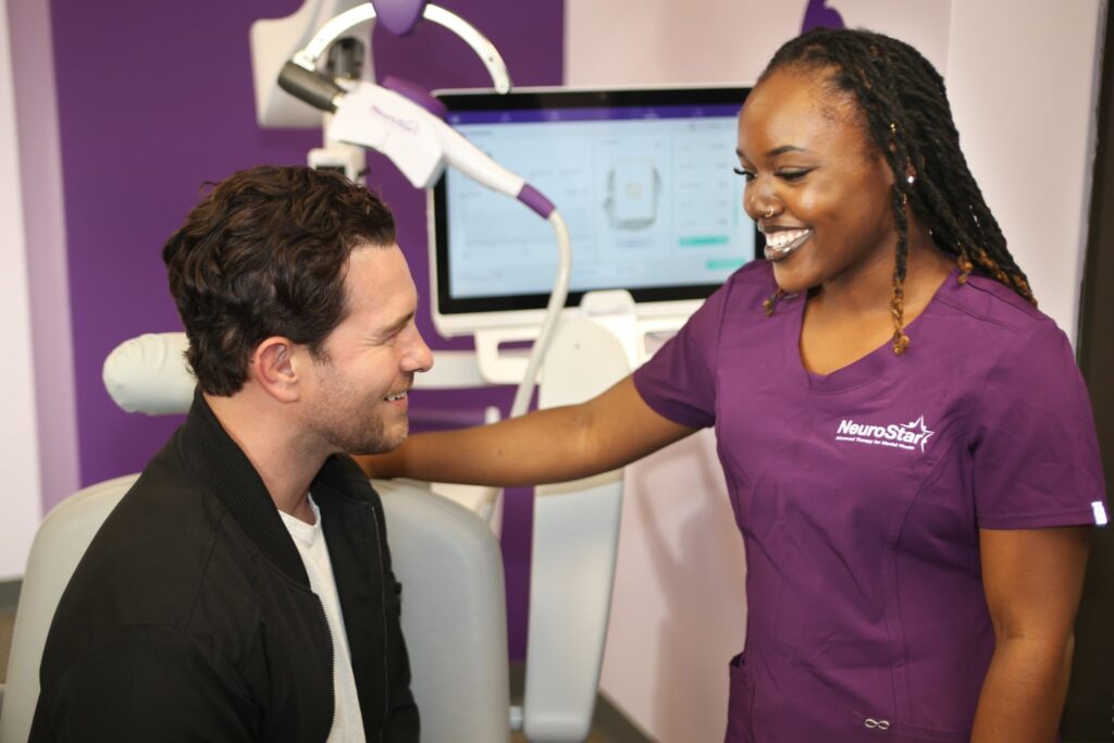 A NeuroStar technician reassures a smiling patient, reflecting hope for those asking can TMS cure depression. 
