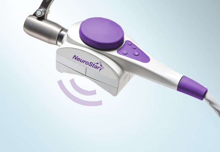 Close-up of a NeuroStar magnetic coil device with purple pad, used in TMS for migraine treatment sessions.